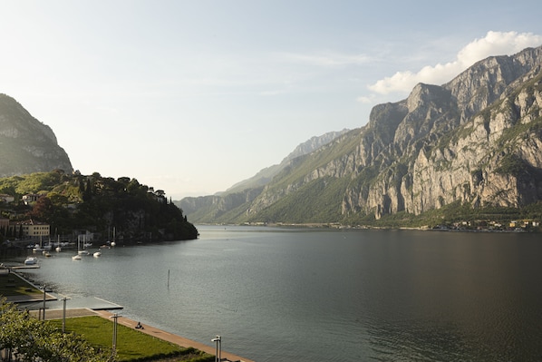 A serene lake with mountains in the background, a marina with boats, and a pathway along the water's edge.