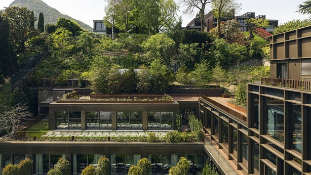 Un edificio moderno con varios niveles, amplias ventanas y un jardín en la azotea.