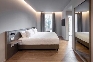 Un dormitorio moderno con una cama grande, una mesita de noche, un televisor de pantalla plana y un espejo amplio.