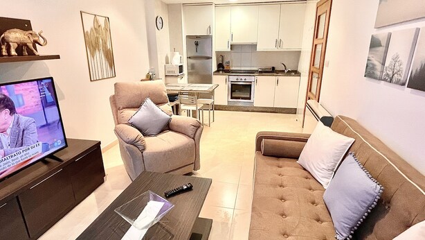A living room with a TV, a sofa, a chair, and a coffee table.