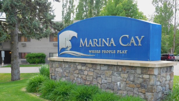 En blå skylt med texten ”Marina Cay” och ”Where People Play”, omgiven av sten och gräs.