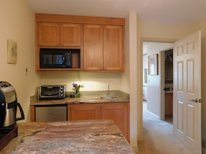 Compact kitchen with microwave, toaster, and granite countertop.