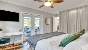 Ein Schlafzimmer mit Bett, Deckenventilator, Fernseher, Schreibtisch und Drucker.