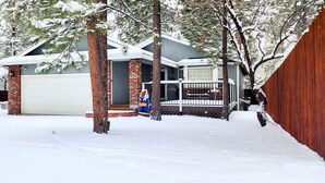 Une maison d’habitation avec un garage, une véranda et une clôture en bois.