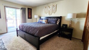 Une chambre à coucher avec un lit, deux tables de chevet, une porte et une fenêtre.