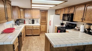 Une cuisine avec des meubles de rangement en bois, un four à micro-ondes, une cuisinière et un réfrigérateur.