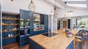 Una cocina moderna con armarios azul oscuro, una isla de madera e iluminación colgante.