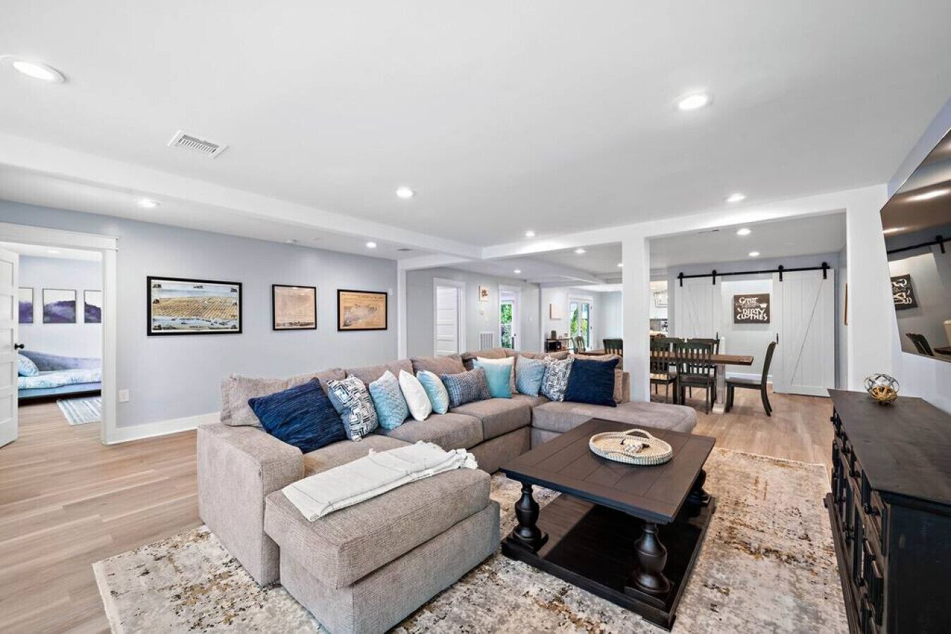 A modern living room with a sectional sofa, a coffee table, and a dining area with a table and chairs.