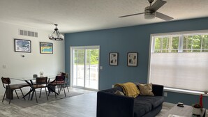 Ein modernes Wohnzimmer mit einem dunkelblauen Sofa, einem Couchtisch und einem Essbereich mit einem Glastisch und Stühlen.