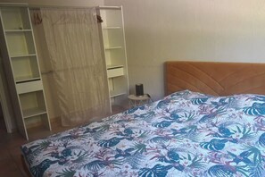 Cozy retreat with a floral-patterned bedspread, a wardrobe with ample storage, and a bedside table with a lamp.