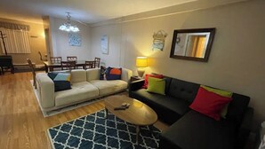 A living room with a sofa, a coffee table, a dining table with chairs, and a lamp. - Cozy Winter Escape (Laconia)