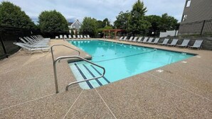 A swimming pool with a tiled deck, surrounded by lounge chairs and a pergola. - Cozy Winter Escape (Laconia)