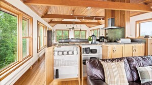 A spacious kitchen with wooden beams, large windows, and a built-in cabinet with glassware.