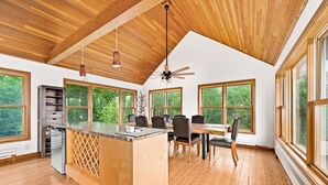 A spacious kitchen with a wooden island, large windows, and a ceiling fan.