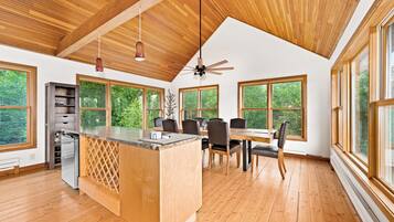 A spacious kitchen with a wooden island, large windows, and a ceiling fan.