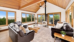 A spacious living area with a high ceiling and large windows offering views of the outdoors.