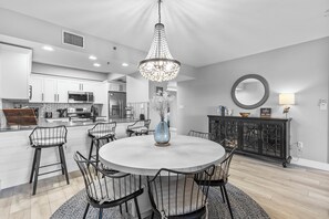 A modern kitchen with white cabinets, a central island, and a dining area with a round table and chairs.