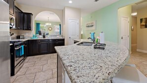 A modern kitchen with dark cabinets, granite countertops, and a central island.
