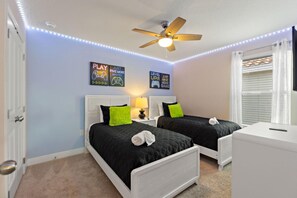A bedroom with two beds, a ceiling fan, LED strip lights, and motivational wall art. - Orange Pineapple at Solterra by Shine Villas 411 (Davenport)