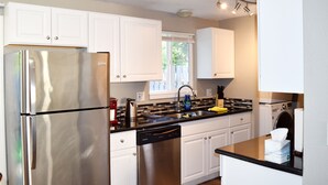 A modern kitchen with stainless steel appliances, white cabinetry, and a black countertop. - Duplex with Backyard and Putting Green (Beaverton)