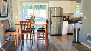 A modern kitchen with wooden chairs, a stainless steel refrigerator, and a dining table. - Duplex with Backyard and Putting Green (Beaverton)