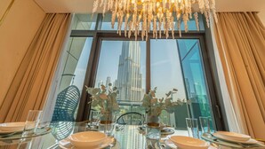 A dining table set for four with a view of a tall building through large windows.