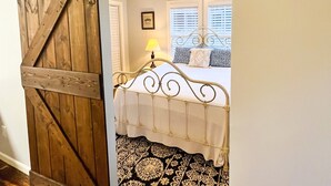 A bedroom with a bed, a ceiling fan, and a patterned rug.