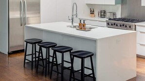 Een moderne keuken met een centraal eiland, roestvrijstalen apparatuur en barkrukken.