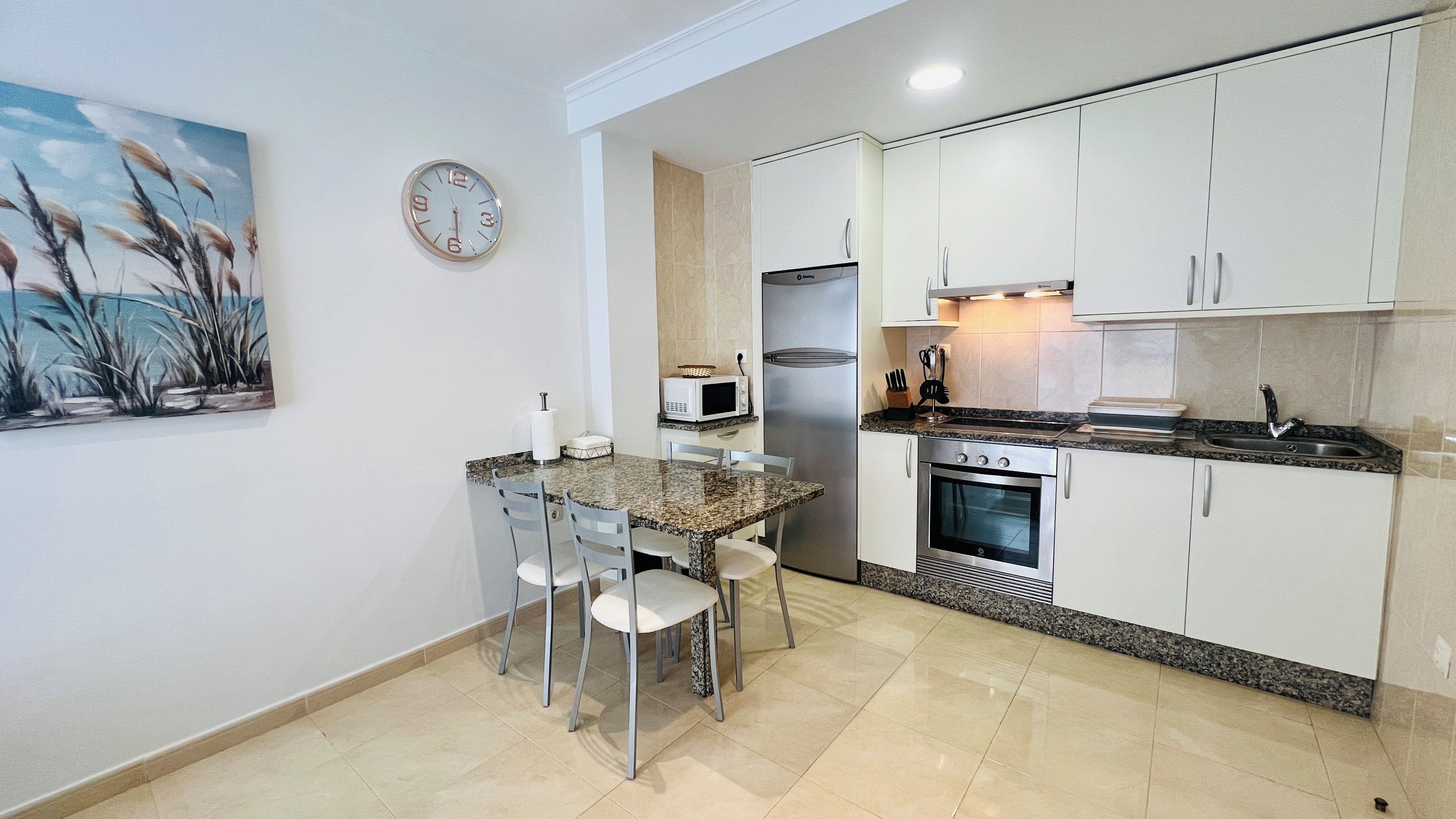 A compact kitchen with a dining area, a microwave, a refrigerator, and an oven.