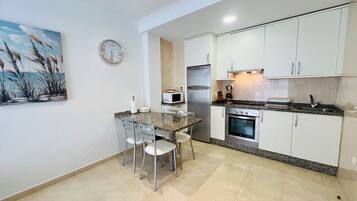 A compact kitchen with a dining area, a microwave, a refrigerator, and an oven.
