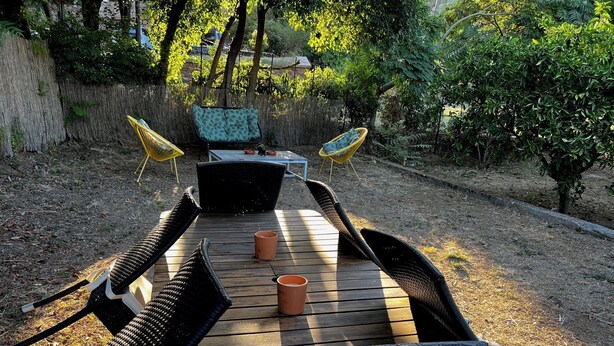 An outdoor dining area with a wooden table and black wicker chairs. - Small vacation villa, beach and barbecue :-) (Bastelicaccia)