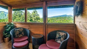Une cabane en bois, dotée de chaises en osier, qui offre une vue sur un paysage verdoyant.