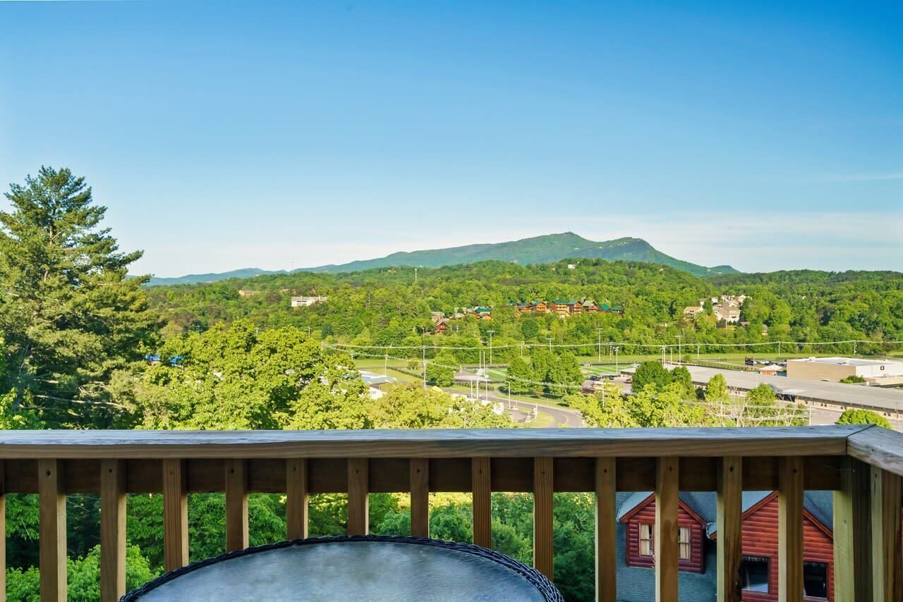 Un balcon donnant sur un paysage verdoyant, une montagne et une route.