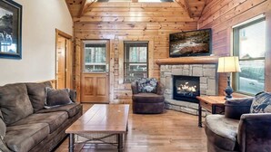L’intérieur d’une cabane en rondins, avec une cheminée, des murs en bois, un canapé et une table à manger.