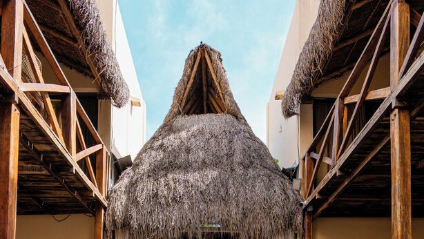 A pool area with a thatched roof structure, wooden railings, and potted plants. - Alma de Zorro (Bacalar)