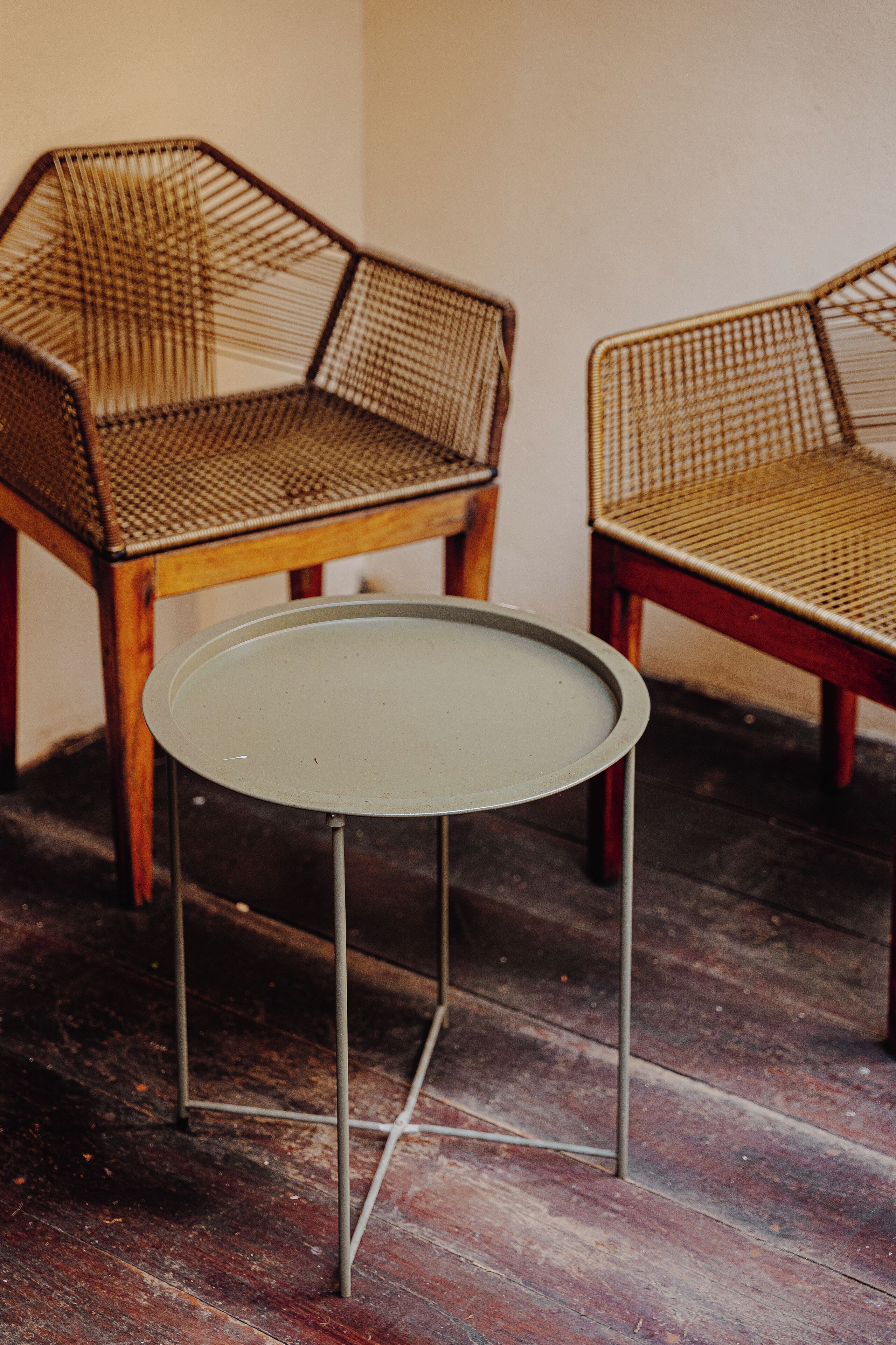 A round table with metal legs and a woven chair with a hexagonal backrest.