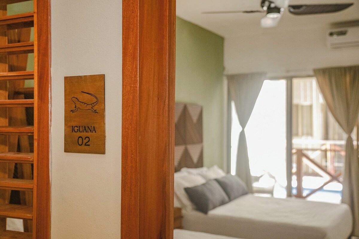 A hotel room with a bed, a wooden shelf, and a sign indicating room number 02.