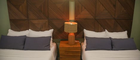 Une chambre d’hôtel avec deux lits, une tête de lit en bois et une table de chevet avec une lampe.