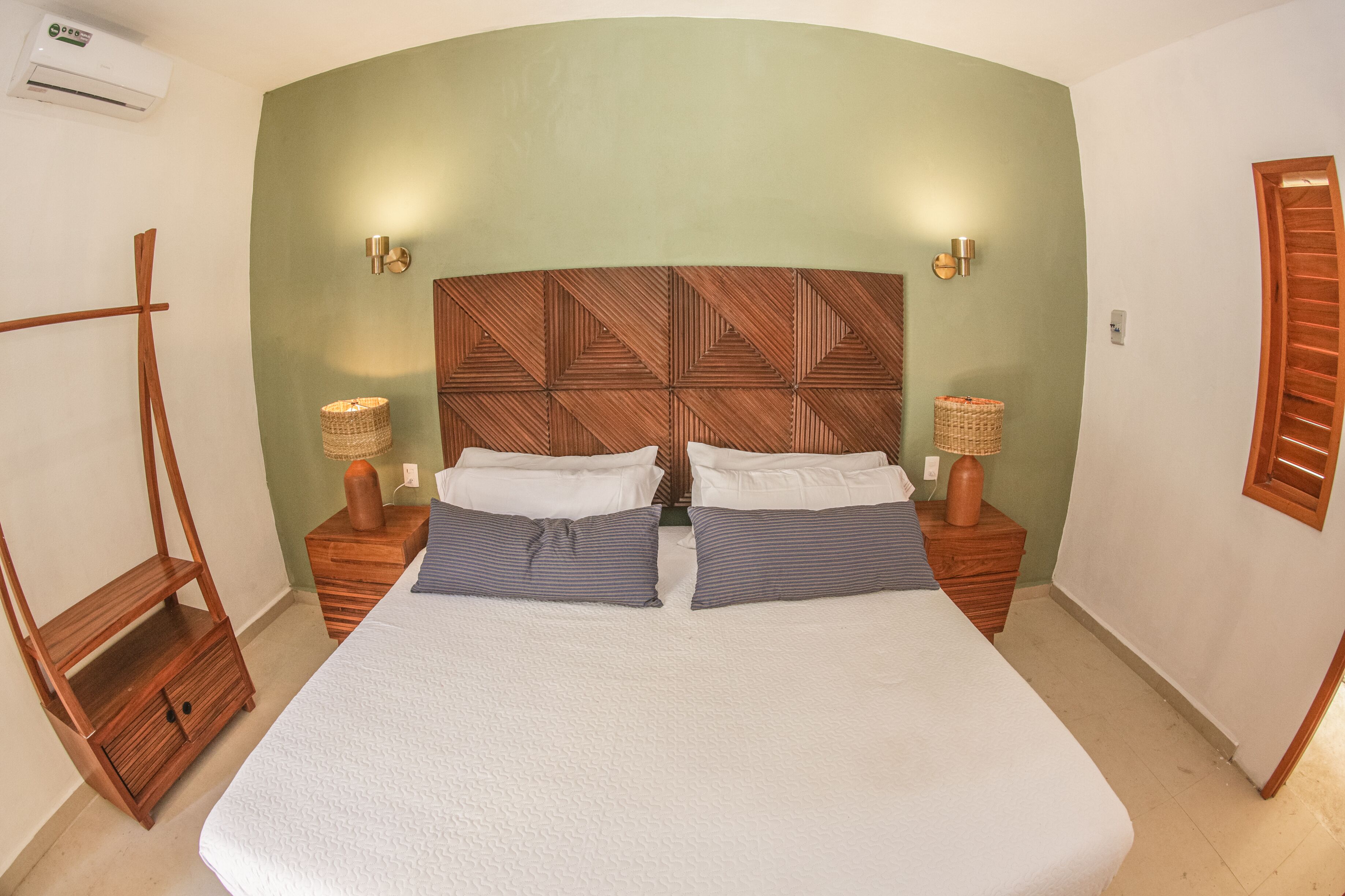 Ein Schlafzimmer mit einem großen Bett, zwei Nachttischen, einem Holzkopfteil und zwei Wandlampen.