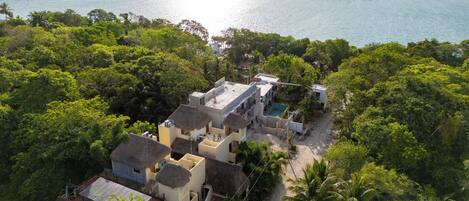 An aerial view of a coastal property with multiple buildings, a swimming pool, and lush greenery.