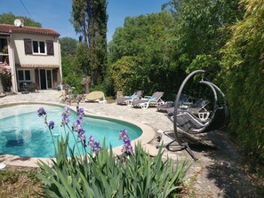 A swimming pool with lounge chairs and a hanging chair, surrounded by greenery and a house. - Studio in a green oasis by the pool (Flayosc)