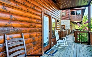 A wooden cabin with a porch, a rocking chair, and a welcome mat.