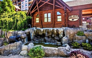 Experience the serene atmosphere of Big Bear Lodge, surrounded by lush greenery and a naturalistic rock garden with a small waterfall.