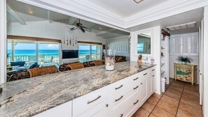 A spacious kitchen with a large island, white cabinetry, and a view of the ocean. - Elegant Coastal Retreat Located at Village Sands~ (Indian Shores)
