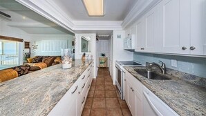 A kitchen with white cabinets, granite countertops, and a tiled floor. - Elegant Coastal Retreat Located at Village Sands~ (Indian Shores)