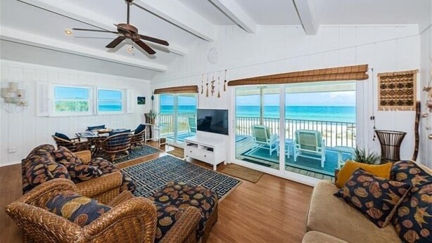 A spacious living room with wicker furniture, a ceiling fan, and a large TV. - Elegant Coastal Retreat Located at Village Sands~ (Indian Shores)