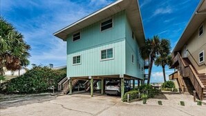 A two-story building with a flat roof, multiple windows, and a covered parking area. - Elegant Coastal Retreat Located at Village Sands~ (Indian Shores)