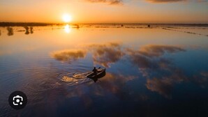 Un plan d'eau paisible, avec un bateau et un coucher de soleil en arrière-plan.