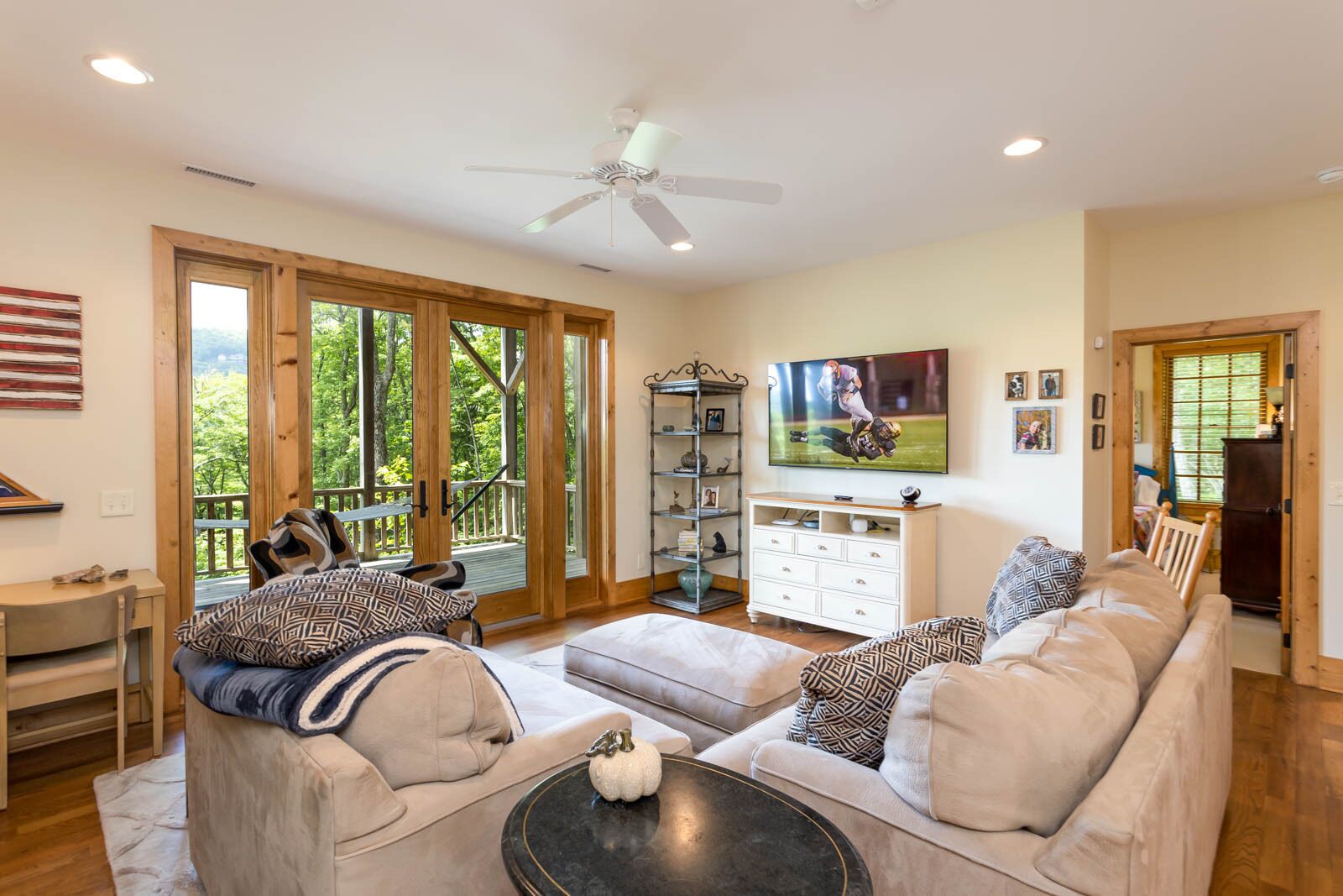A spacious living room with a large sofa, a coffee table, and a TV mounted on the wall.