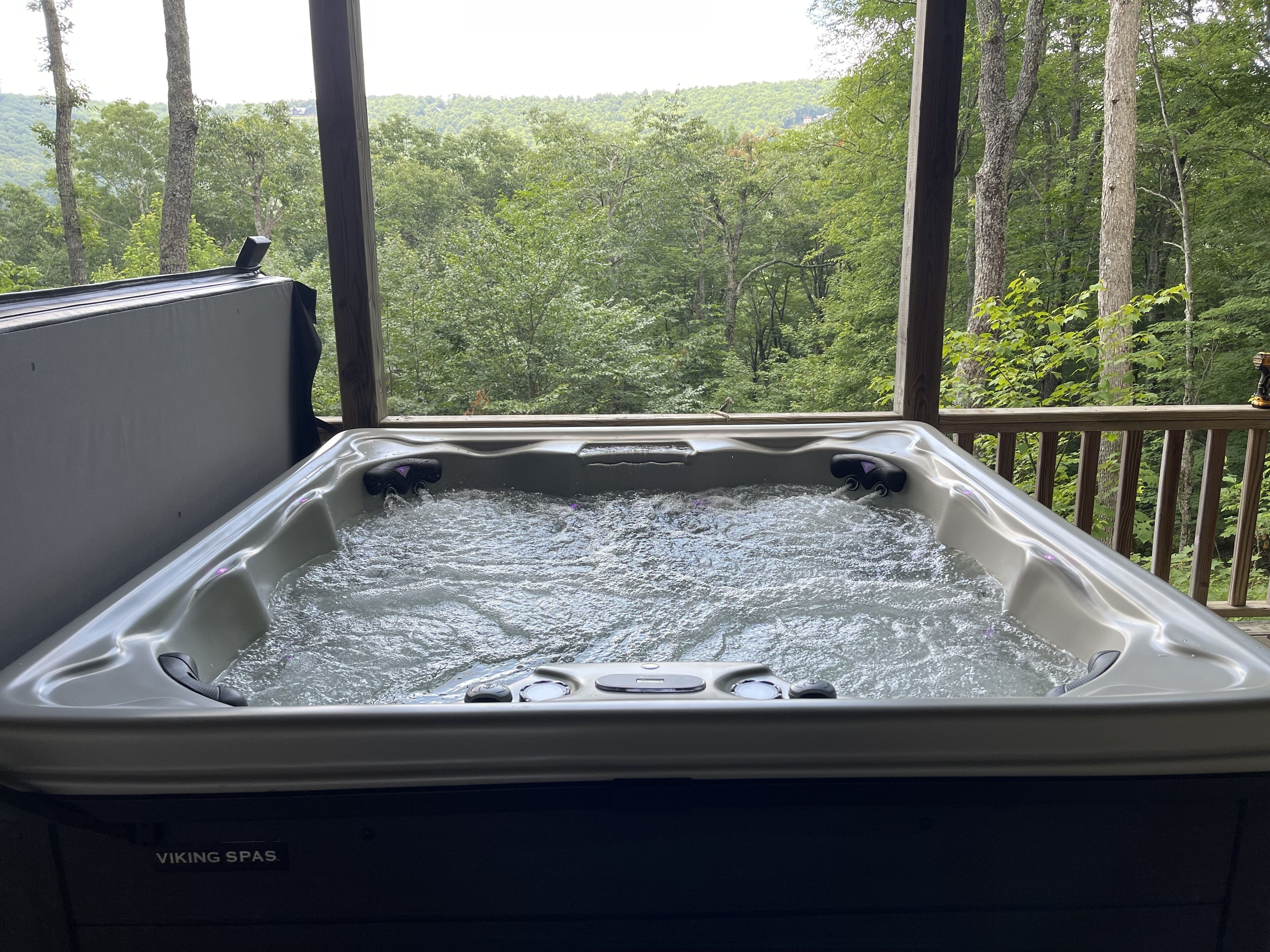 A hot tub with a view of a forested landscape.